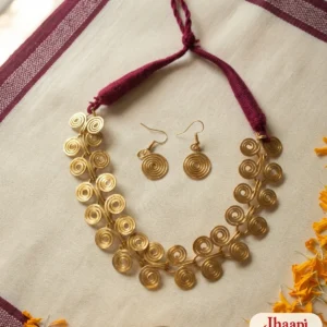Brass spiral hasuli necklace with a twisted maroon cord and round spiral earrings laid flat on a maroon-bordered handloom cloth with marigold petals
