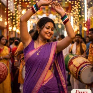 Smiling woman in a purple handloom saree dancing to the dhak at a lit-up pandal, arms raised, wearing the multicolour thread bangles on both wrists