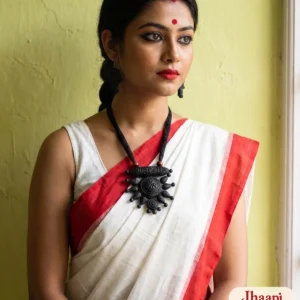 Woman in a red-bordered white saree wearing the Jhaapi black terracotta dhol chakra necklace and matching earrings