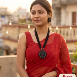 Woman in a red handloom saree on a Kolkata rooftop wearing the Jhaapi black terracotta chakra necklace and matching earrings