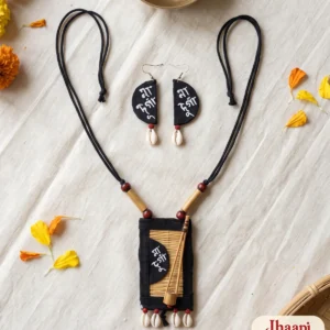 Madur Maa Durga necklace with bamboo beads and cowrie fringe and the matching half-moon earrings laid flat on handloom with marigold petals, a brass bowl and a cane basket